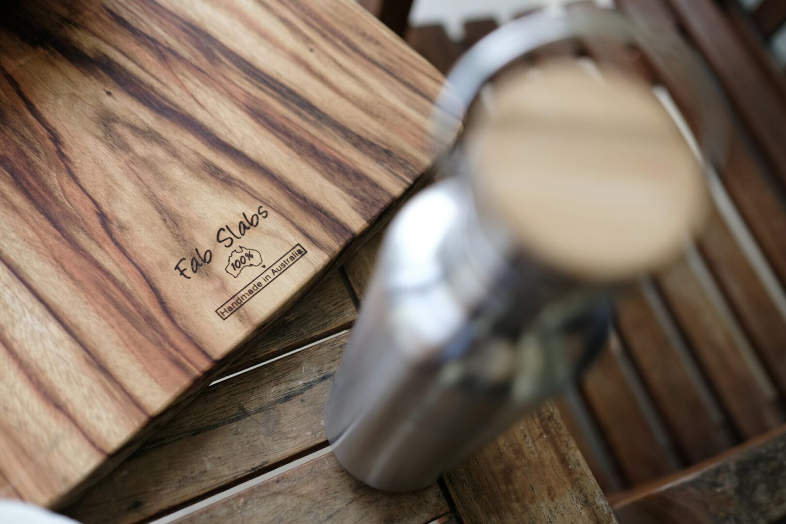 A wooden cutting board and a metal can on top of a table.
