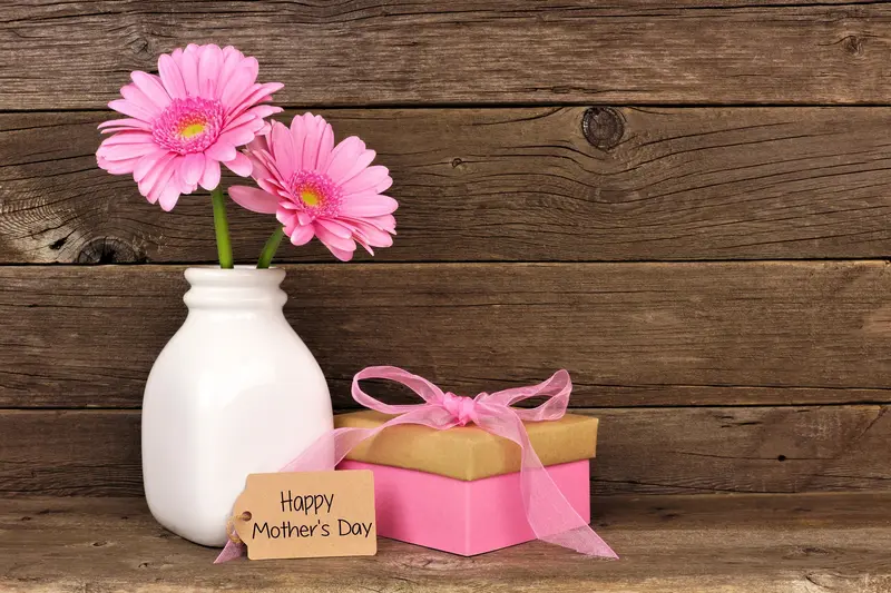 A vase with pink flowers and a gift box.